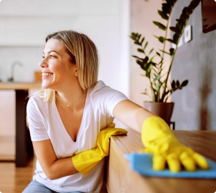 Woman in a mask sanitizing an office desk.